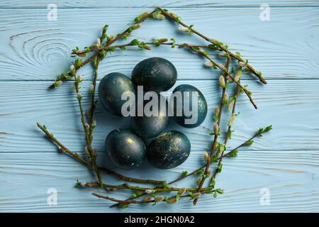 Easter eggs in a frame of branches on a blue wooden background. Minimalistic spring easter concept. Stock Photo