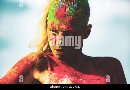Portrait of fashion woman in colored powder holi. Woman face painted in the colors of Holi festival. Holi paint party.