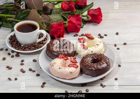 Handmade donuts on a light background in white and black chocolate. There are flowers nearby. Women's day, Valentine's day. copy space. Stock Photo