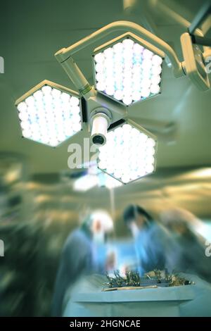 Bright light in the surgery room on the background of working surgical team. Stock Photo