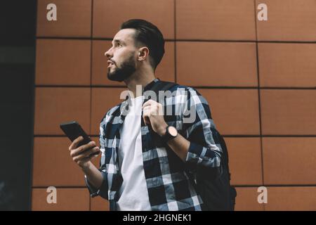 pensive male blogger with mobile gadget looking away Stock Photo
