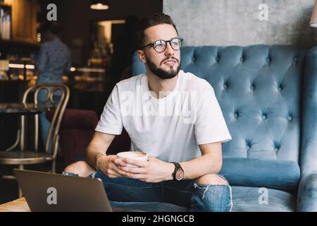 contemplative hipster guy in eyeglasses pondering on ideas for web design Stock Photo