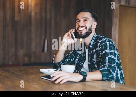 Cheerful Caucasian man using cellphone device for calling enjoying positive conversationv Stock Photo