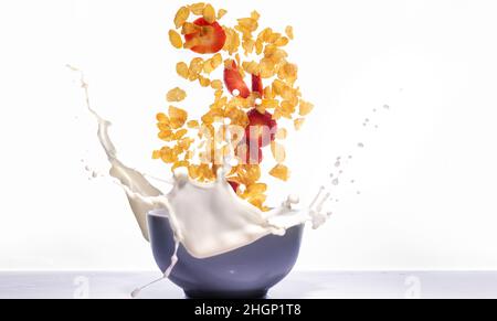 Corn flakes with strawberries falling and splashing into a bowl with milk Stock Photo