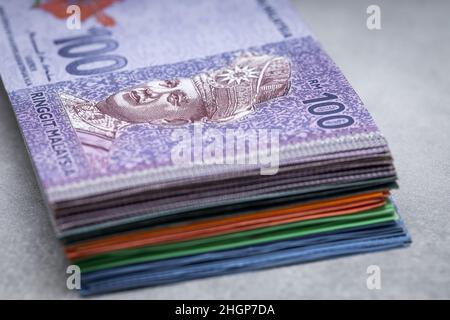 A bundle of Malaysian money, ringits on a gray table top, 100 banknote on top, Economic and business concept Stock Photo