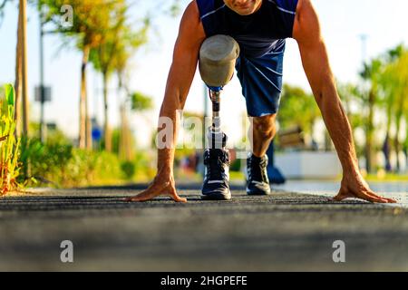 disabled athlete man with prosthetic leg starting to run at the beach on a treadmill outdoors at sunset Stock Photo