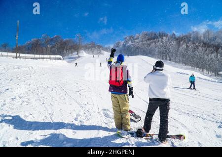 Two snowboarders snowboarding in mountain. Snowboarders enjoying leisure activities on outdoors. Group of friends enjoying the winter season. Stock Photo