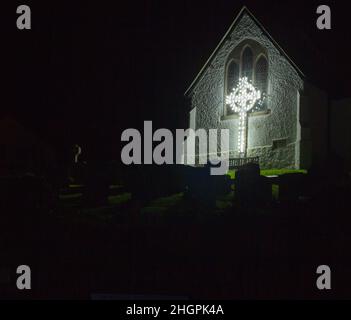 Celtic cross in lights at St Peter's church, Coverack, Cornwall.  Part of the annual Christmas lights display. Stock Photo
