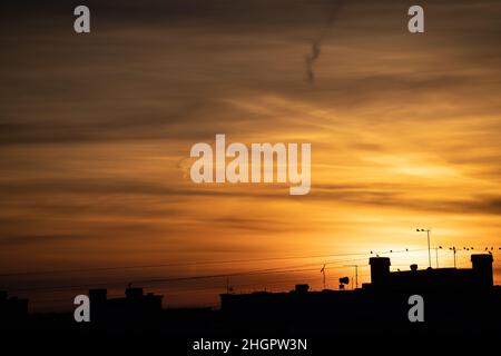 Landscape scenery of autumn sunset sky over silhouette of top of houses with chimney pots and tv antennas aerials. Colourful Sunset sky with yellow or Stock Photo
