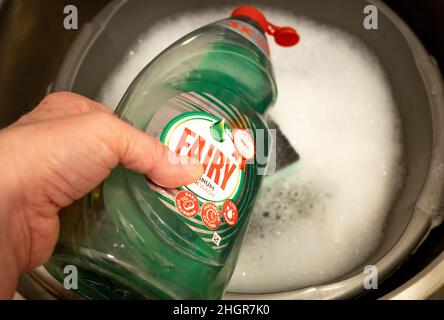 Norwich, Norfolk, UK – January 2022. Unidentifiable male using Fairy Platinum quick wash detergent to wash the dishes Stock Photo