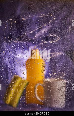 View through dirty glass. Close-up of household cleaning products and kitchen accessories. On a dark lilac background. High quality photo Stock Photo