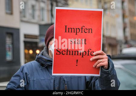 Dussedorf, NRW, Germany. 22nd Jan, 2022. Impfen statt Schimpfen' (vaccinate, don't moan) placard. A protest against compulsory vaccination, and related subjects marches through Dusseldorf city centre today, the capital of North Rhine-Westphalia. The march is met by groups of pro-vaccination, pro covid measures groups from activist and political groups as well as some pro-immigration and antifa protesters. Credit: Imageplotter/Alamy Live News Stock Photo