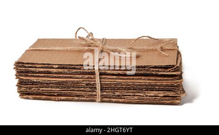 Tied pile of corrugated fiberboard ready for recycling isolated on a white background. Waste paper Stock Photo