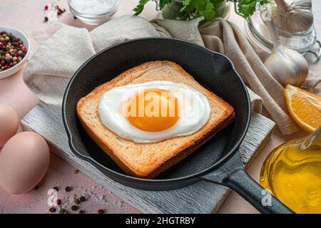 Fried eggs on a light background in a frying pan. Side view, close-up. Stock Photo