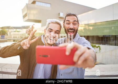 Happy gay couple taking smiling selfie with smartphone. Homosexual people having fun together. Stock Photo