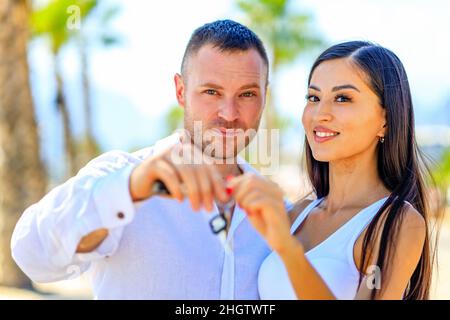mixed race couple in love holding the keys in a hands in sunny summer day ourdoors Stock Photo