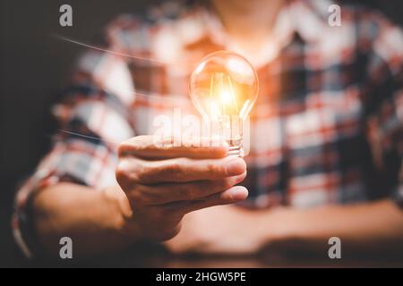 Man hand holding light bulb with line connect and working on the desk, Creativity and innovation are keys to success.Concept of new idea and innovatio Stock Photo