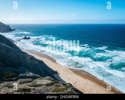 Turquoise waves crashing on Praia do Castelejo beach in the Algarve region of Portugal