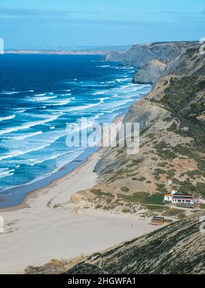 Turquoise waves crashing on Praia do Castelejo beach in the Algarve region of Portugal