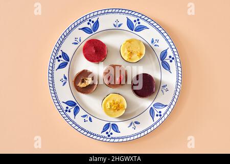 Blueberry, raspberry, goji, lemon and banana raw vegan mini desserts on a plate, top view Stock Photo