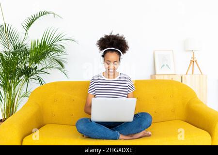 African american girl working on laptop while sitting on couch at home Stock Photo