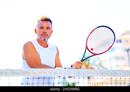 Senior tennis player playing tennis outdoors im sunny day Stock Photo