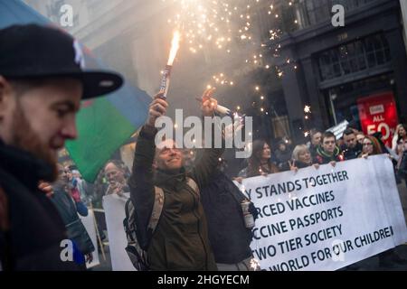 London, UK. 22nd Jan, 2022. A protester holds up a burning flare while marching through central London during the demonstration. Protesters marched through central London during a worldwide rally for freedom - protesting against government restrictions surrounding Covid 19 including mandatory vaccinations, particularly with NHS staff, who may face losing their job if they refuse to get vaccinated. (Photo by Christopher Walls/SOPA Images/Sipa USA) Credit: Sipa USA/Alamy Live News Stock Photo