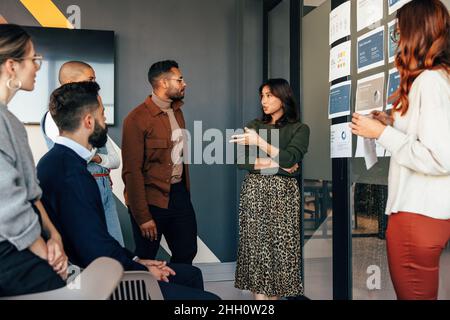 Female manager having a discussion with her business team. Group of multicultural businesspeople having a meeting in a modern office. Diverse entrepre Stock Photo