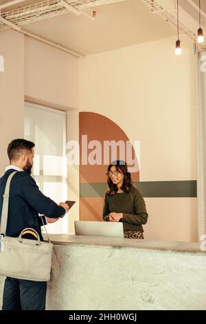 businessman signing in to an office at the front desk. Modern businessman putting his signature on a digital tablet. Young entrepreneur registering fo Stock Photo