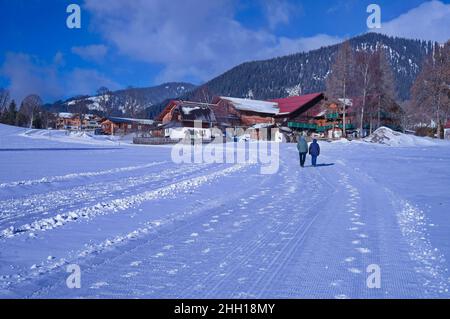 Two people walking through the village in wintertime Stock Photo