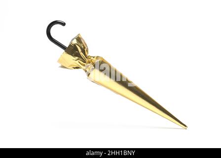 Close up of chocolate umbrella wrapped in gold paper with black handle on white background Stock Photo