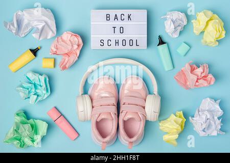 Back to school text on lightbox. Headphones, pink shoes, colored crumpled paper balls, marker on blue background. Education concept. Flatlay Top view Stock Photo