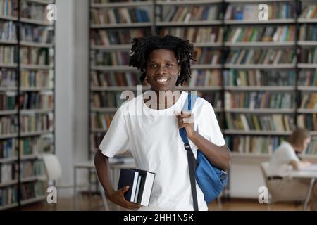 Happy African American student guy with dreads in college library Stock Photo