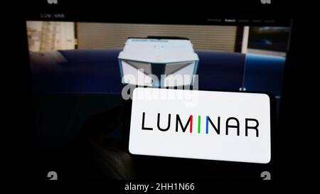 Person holding cellphone with logo of US lidar company Luminar Technologies Inc. on screen in front of business webpage. Focus on phone display. Stock Photo