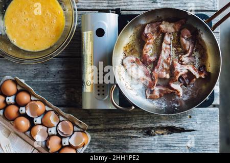 breakfast setup top down with eggs, shells, bacon on camp stove Stock Photo