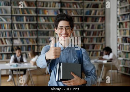 Happy teen student in eye glasses and backpack holding books Stock Photo