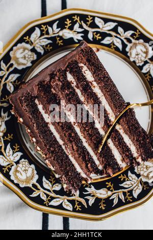 Devil's Food chocolate layer cake on black white gold plate with gold fork Stock Photo