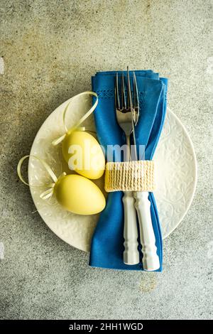 Festive table setting for holiday Easter dinner with yellow eggs and blue napkin Stock Photo