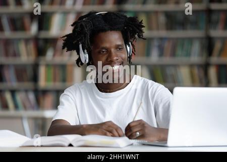 Happy African student guy in headphones watching learning webinar Stock Photo
