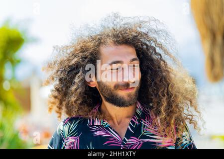 mixed race man with curly long hair outdoors ar sunny day Stock Photo