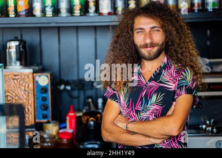 long curly haired mixed race man barman making beverage alcoholic drink at beach shack in tropic Stock Photo