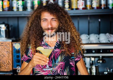 long curly haired mixed race man barman making beverage alcoholic drink at beach shack in tropic Stock Photo