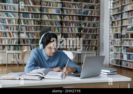 Focused nerdy smart student in glasses and headphones working hard Stock Photo