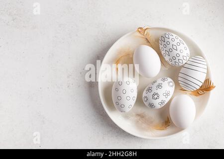 white plate with black and white decorated Easter eggs, feathers Stock Photo