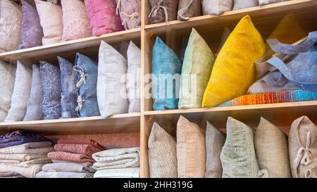 Bright pillows, towels, plaids, blankets and other home wear on shelves Stock Photo