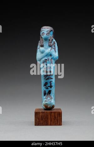 Shabti of Shedsuhori ca. 980–930 B.C. Third Intermediate Period Mold-made 'worker' shabti of blue faience. The figure is mummiform, with a slender cylindrical body from which the head, arms, hands, and feet emerge. The tripartite wig (longer in the back than in the front) is colored a solid purple-black, and crude eyes and eyebrows have been painted on the small face. The wrist are crossed over the chest, and each hand holds a hoe in dark purple-black paint. An inscription down the center of the body and legs and running onto the top of the feet reads 'The illuminated, Osiris Shedsuhori, true Stock Photo