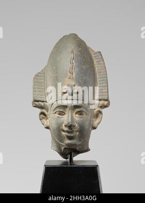 Head from a figure of Osiris ca. 664–525 B.C. Late Period (Saite) This head is from a statuette of Osiris, principal god of the afterlife and ruler of the Netherworld. The deity is shown wearing his typical 'atef' crown, a tall crown flanked by ram's horns and ostrich plumes and protected by a hooding cobra. His face is placid and his serene affect enhanced by a slight smile. Only the very top of his false beard and the straps that would have held it in place are preserved. The tip of the crown, as well as the tops of the feathers and the tips of the horns that flanked it are gone, and the hea