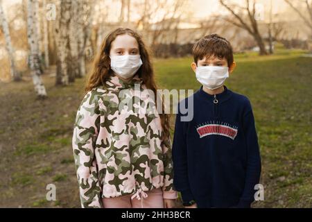 Children in a medical mask outdoors. Pandemic, virus, health concept. Stock Photo