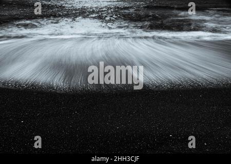 The sand on this beach was already so dark that it inspired me to make a long-exposure monochrome shot of the receding waves. Stock Photo