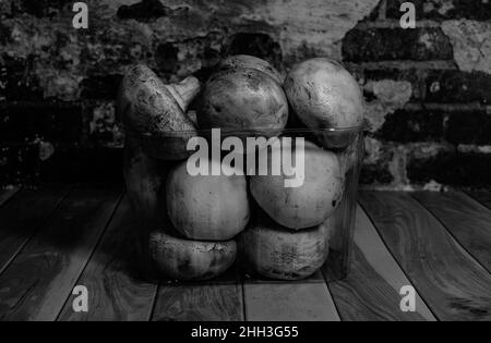 Fresh champignons lie on the table against the background of a brick wall black and white photography close-up Stock Photo